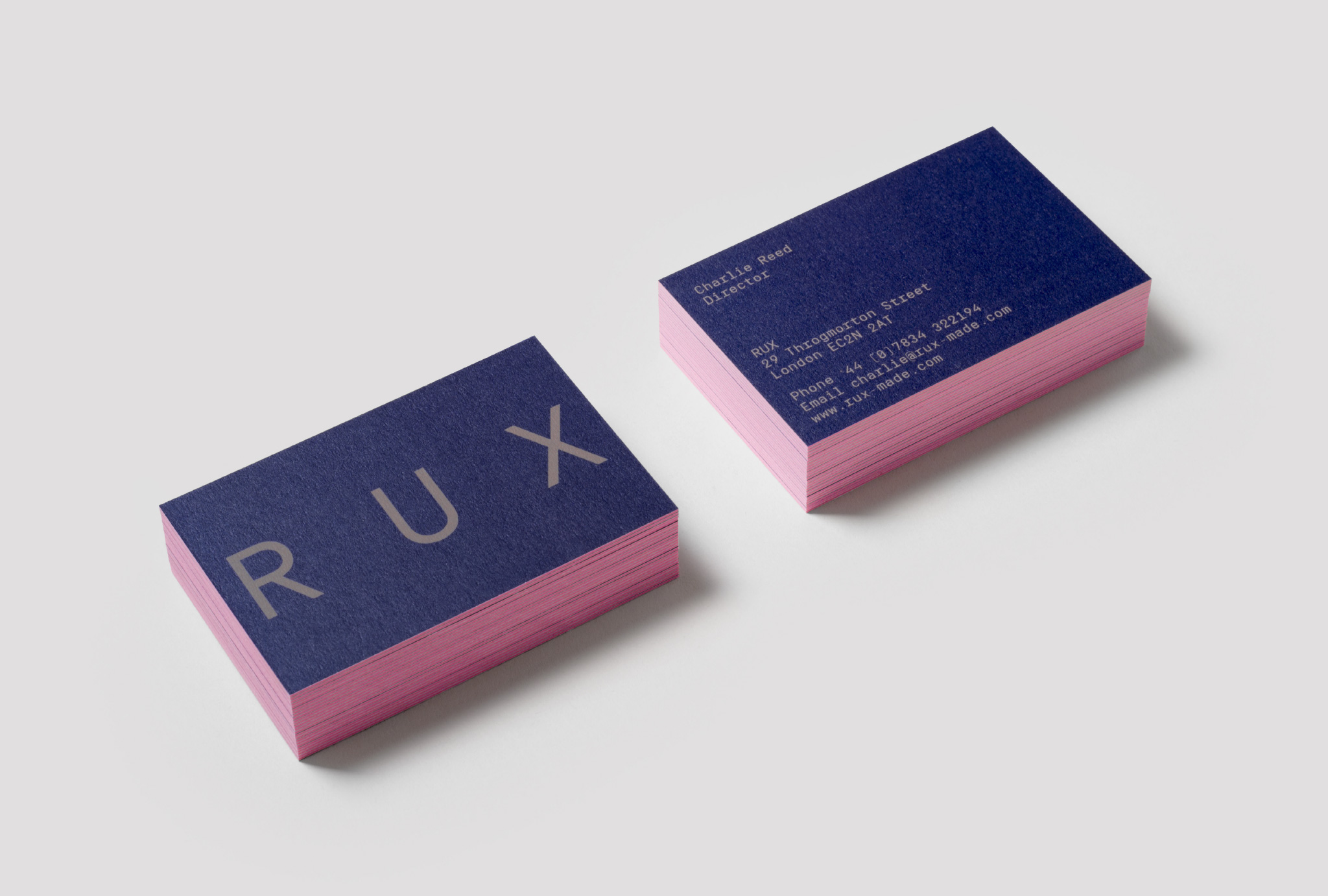 two piles of dark blue business cards with pink sides