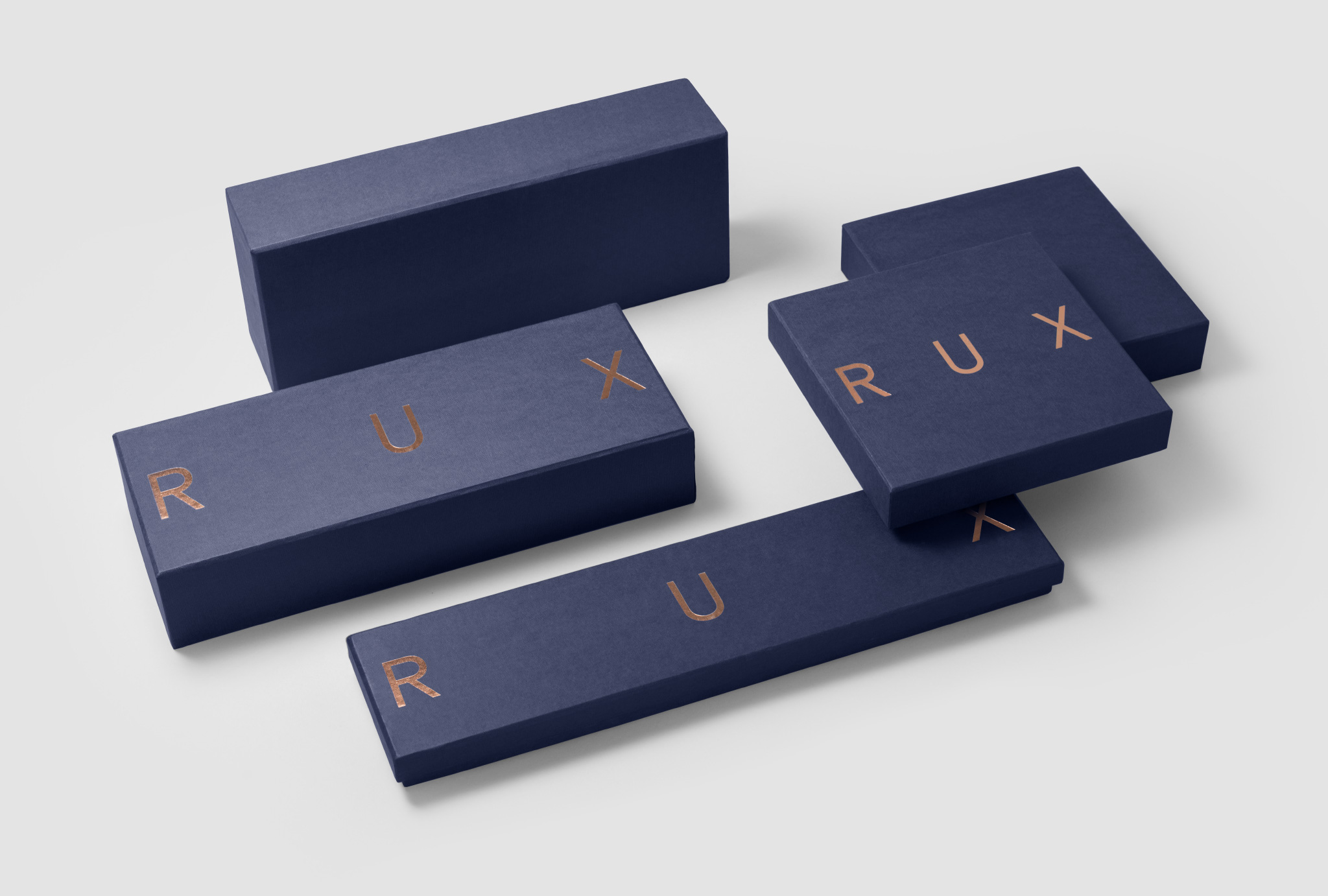 different sizes of dark blue boxes with ‘RUX’ written in copper