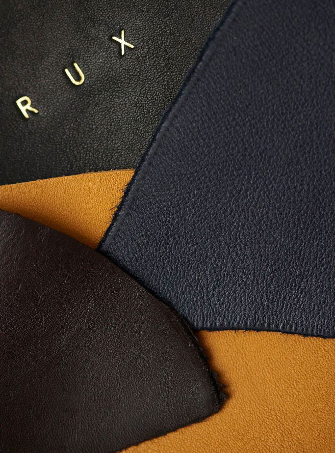 close up on leather in yellow, dark blue and black with ‘RUX’ logo foiled in gold