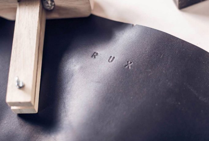 ‘RUX’ logo stamped into black leather