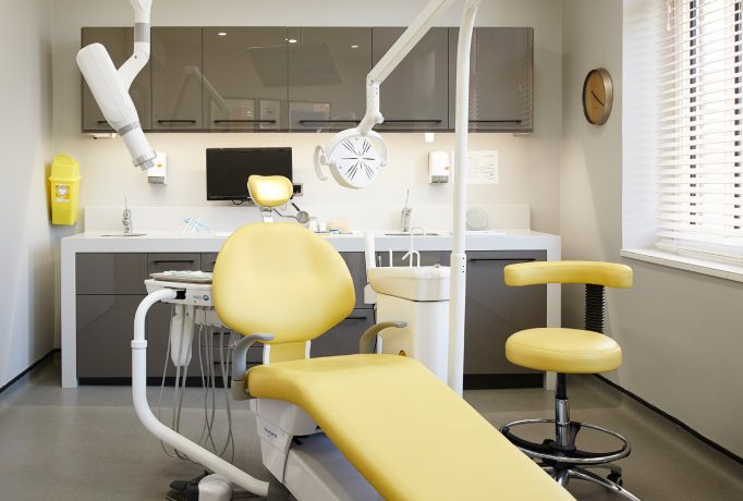 yellow dentist chair in front of a dark grey counter