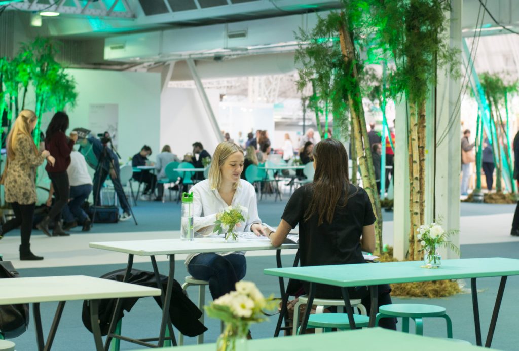 exhibition design with tables and chairs, some plants around with green lights