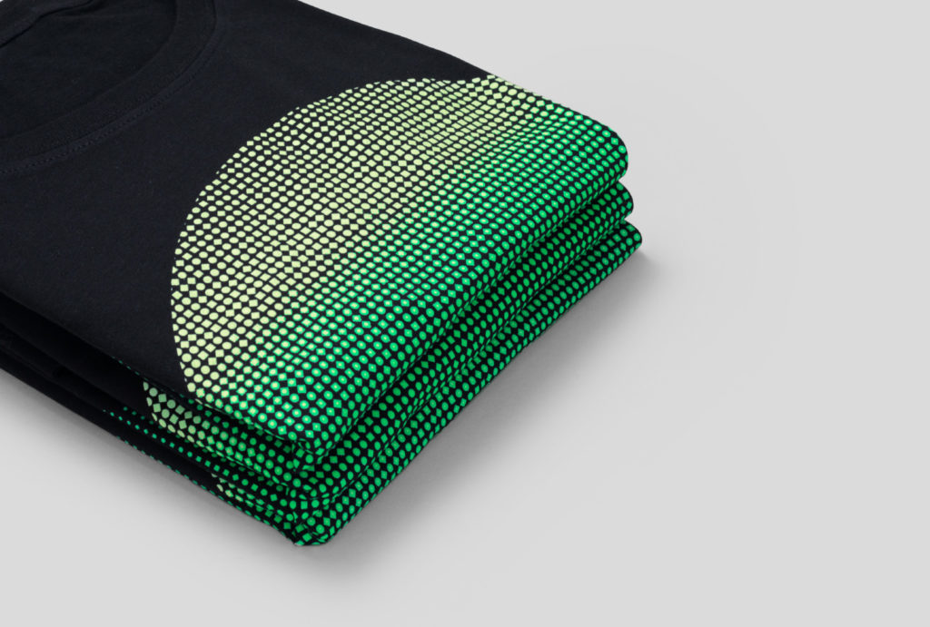pile of folded black t-shirts with printed green circle